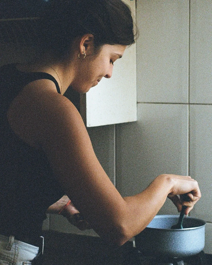 Mica de costas em frente ao fogão, durante o preparo de uma receita