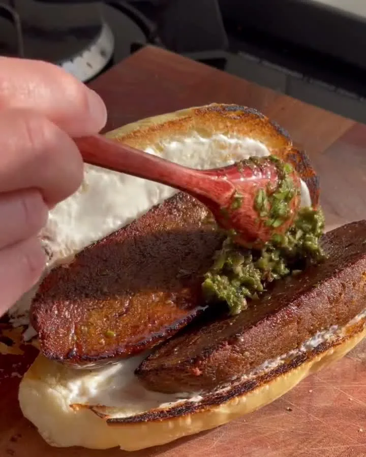 Choripan vegano sendo servido sobre uma tábua de madeira