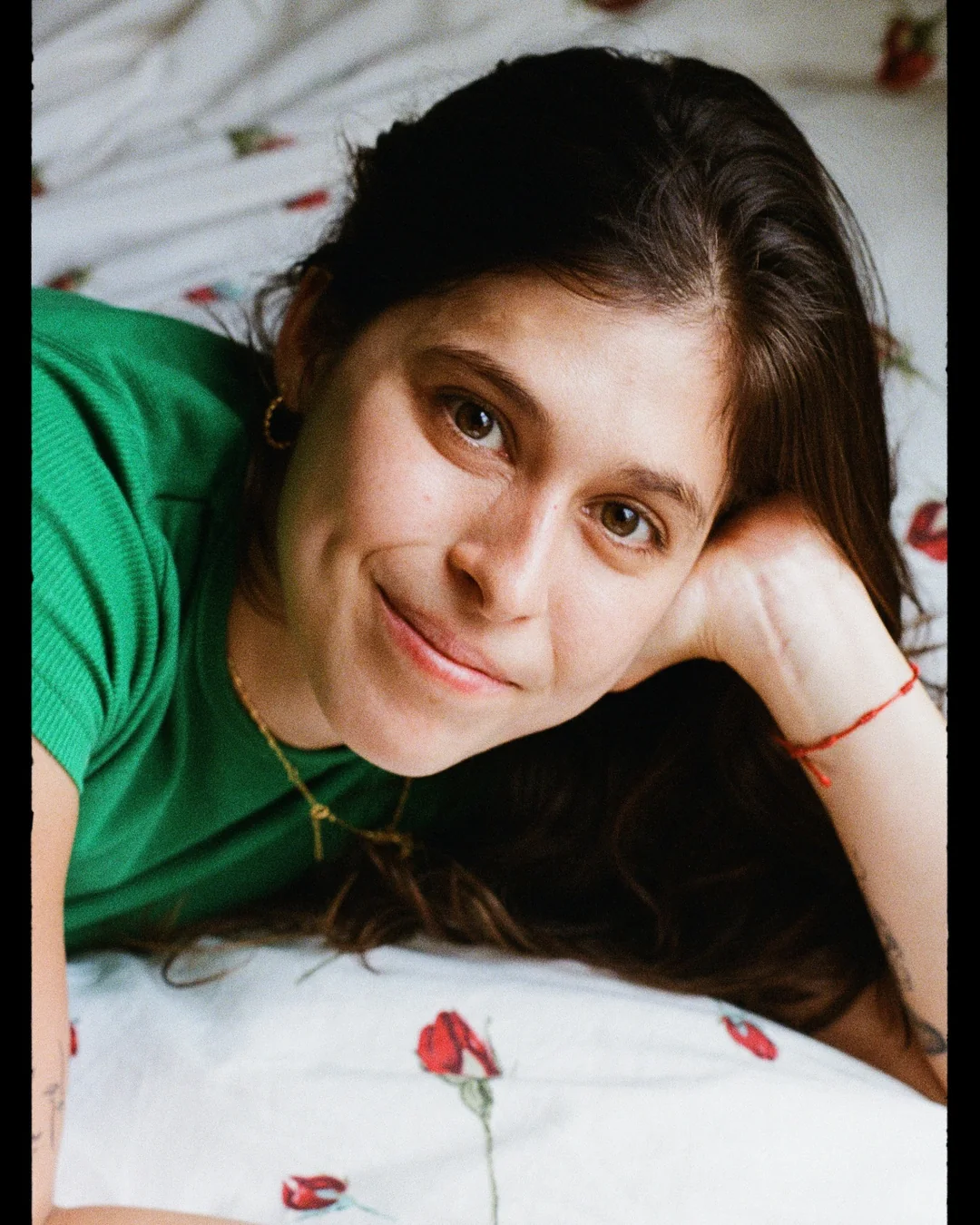 Mica de blusa verde, apoiada na mão, olhando para a câmera em um retrato espontâneo